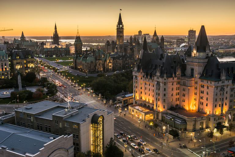 Aerial view of downtown Ottawa at dusk, with the Parliament Buildings highlighted in the background.