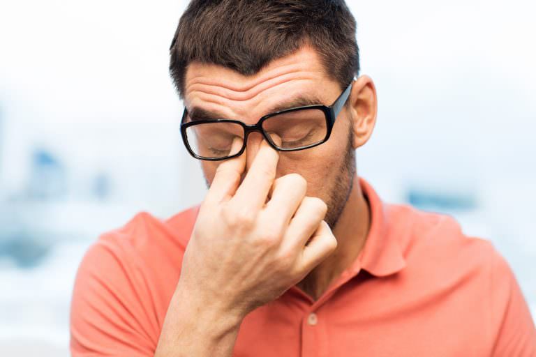 A man rubs his eyes while suffering from visual stress.